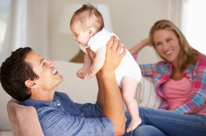 smiling seated parents with Dad lifting baby